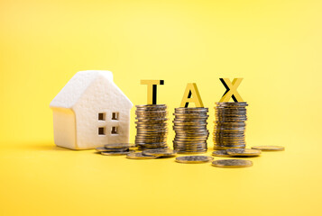 Property tax, home investment, interest rates, mortgage rates, real estate concept. 3d letters T, A and X, on coins stack near white small house toy, isolated on yellow background, minimalist.