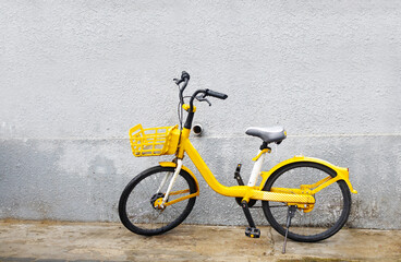 Vintage old yellow bicycle leaning against dirty old wall background. Rental bike on decay wall...