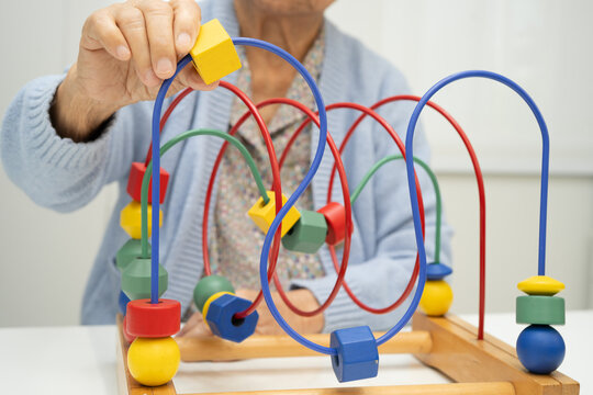 Asian elderly woman playing enhancing skill board game.