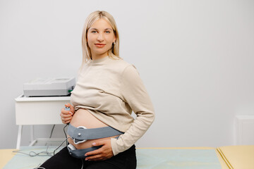 Woman pregnant checking fetal heart beat by fetal monitoring. Expectant mother with midwife...