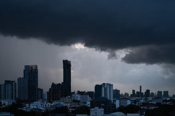 Dark clouds cover the sky before rain with tall buildings of city background when monsoon season.