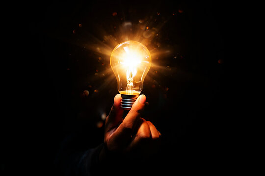 Glowing incandescent bulb held by hand light bright
