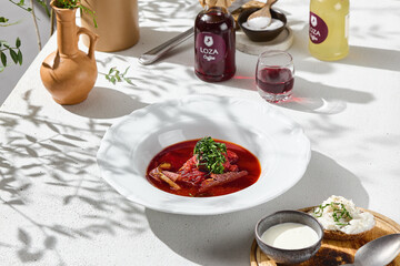 Beef borscht served in a white bowl, bright daylight, overhead flatlay composition