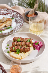 Kebab skewers on pita bread with pickled cabbage, bright daylight, overhead serving composition