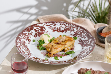 Cornish hen with mashed potatoes, bright midday, overhead composition with patterned plate
