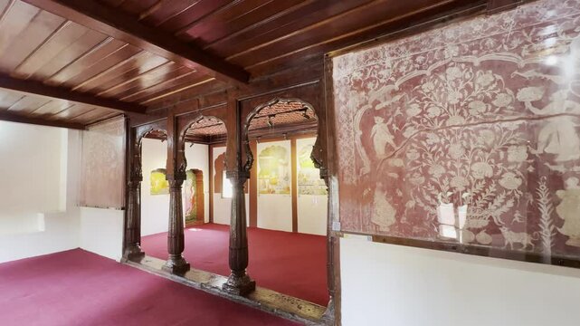 A slow pan reveals a beautiful painting hanging on the wall beneath a traditional wooden ceiling inside a room at Nana Fadnavis Wada, Wai, Maharashtra, showcasing the heritage ambiance and artistry 4K