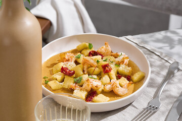 Gnocchi with shrimp and sun-dried tomatoes in bright natural light, minimal overhead composition