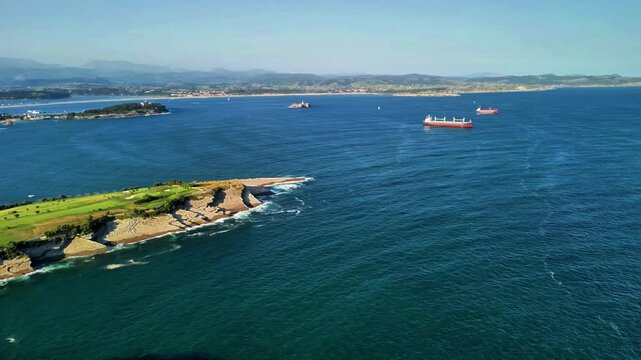 This stunning aerial view showcases a picturesque coastal landscape with lush greenery and ships sailing on the sea