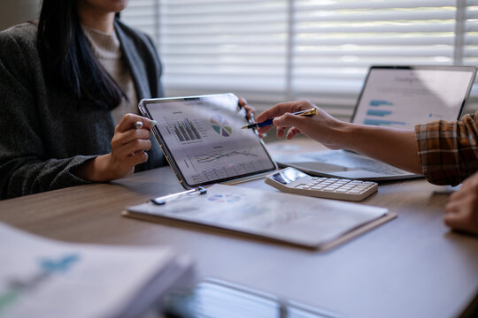 Two people are looking at a tablet with graphs on it