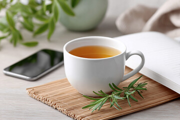 Digital Detox and Offline Retreat concept. Warm cup of tea with herbs on a wooden mat beside a smartphone.