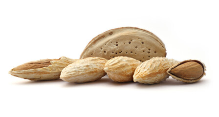 A line of whole raw almonds in shells with one cracked open on white background.