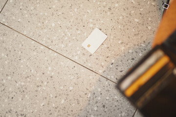 Card dropped on tiled floor near wallet during busy day