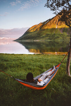 Weekend camping trip outdoor - man chilling in hammock travel lifestyle summer vacation in Norway, traveler enjoying tranquil sunset view of mountains and fjord harmony with nature sustainable tourism