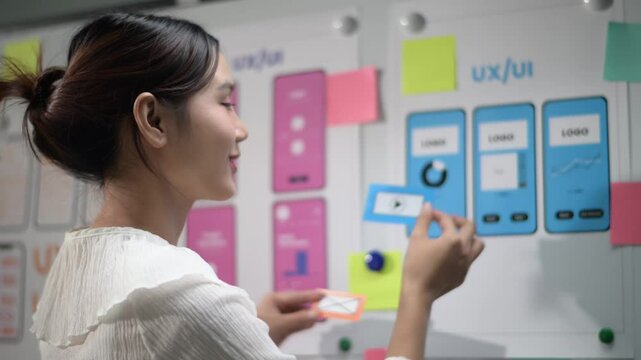 Designer creating ux/ui mockups on board with sticky notes
