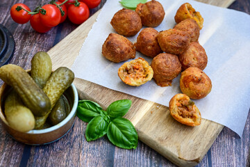 Mini cheese  burger balls.  Ball shaped snack with meat, pickled cucumbers and tomato on wooden...