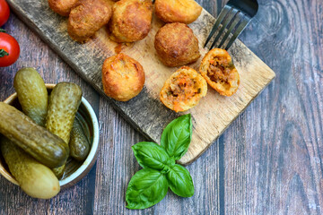 Mini cheese  burger balls.  Ball shaped snack with meat, pickled cucumbers and tomato on wooden...