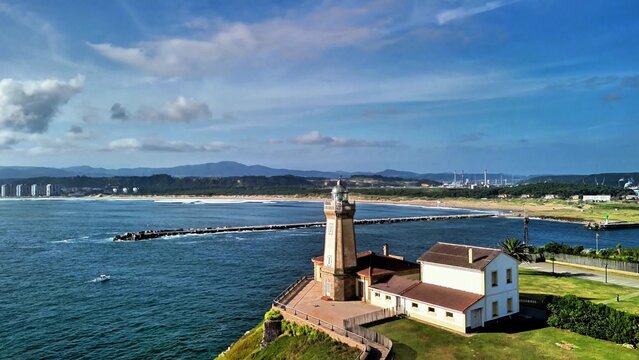 There is a stunning view of a coastal lighthouse gracefully standing beside a serene pier and beautiful beach landscape