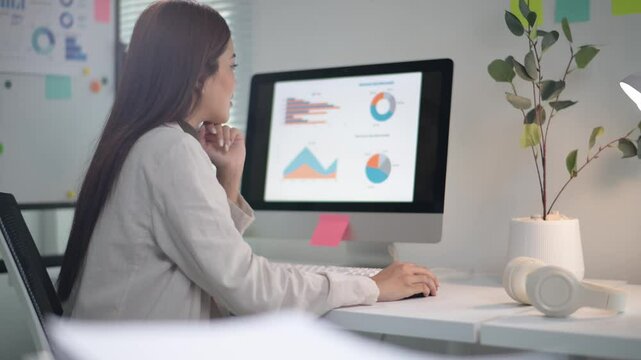 Businesswoman analyzing charts on computer at her desk