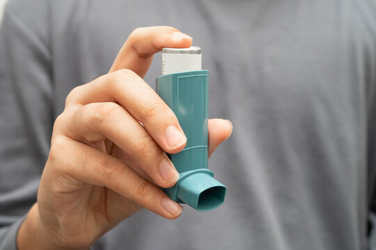 Asthma and chronic obstructive pulmonary disease COPD, Asian young man using metered dose inhaler MDI.