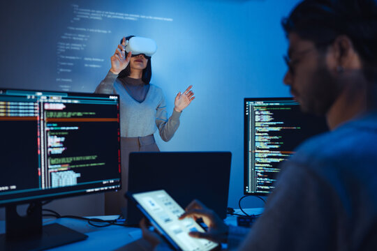 developer uses a VR headset to interact with projected interface designs, while colleagues discuss and code on screens,virtual reality and UI/UX design in modern software development