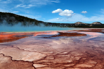 Fototapeta premium A grand prismatic spring, shot against the background of forests, mountains and clouds.