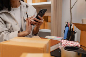 an entrepreneur is packing parcel for order from customer, she own a small business, sme, a lot of package in the room, e-business is running by a this entrepreneur, online shopping