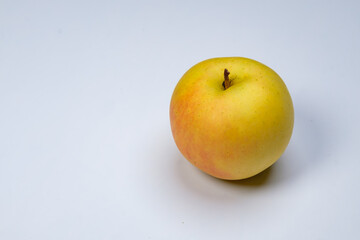a whole flesh yellow-red orin apple  covered with small water droplet with shadow from backlight a...
