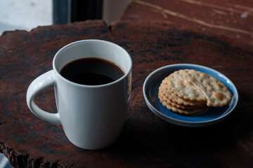black hot coffee served with wheat crackers on dark wooden table