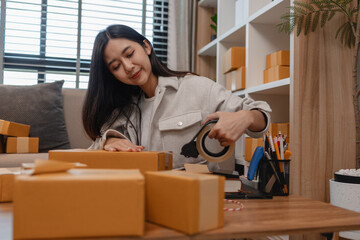 she is packing parcel to send to all customers, this entrepreneur own a small business, sme, selling product online, she prepare her product in her office, packing order