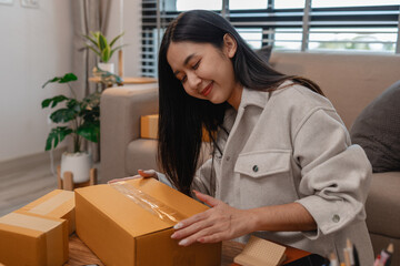 she is packing parcel to send to all customers, this entrepreneur own a small business, sme, selling product online, she prepare her product in her office, packing order