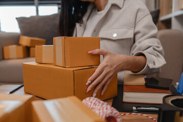 she is packing parcel to send to all customers, this entrepreneur own a small business, sme, selling product online, she prepare her product in her office, packing order