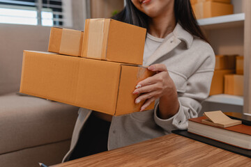 she is packing parcel to send to all customers, this entrepreneur own a small business, sme, selling product online, she prepare her product in her office, packing order