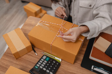 she is packing parcel to send to all customers, this entrepreneur own a small business, sme, selling product online, she prepare her product in her office, packing order