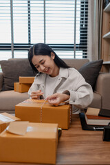 she is packing parcel to send to all customers, this entrepreneur own a small business, sme, selling product online, she prepare her product in her office, packing order