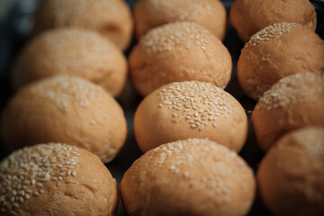 many baked sesame topping burger breads lay on oven tray waiting for cooking, shot with shallow focusing  for using as background wallpaper