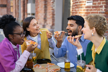 A diverse group of friends happily eating pizza together outdoors, enjoying a meal and each other's company.