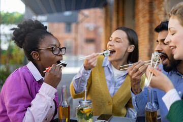 A diverse group of friends enjoys sushi outdoors, a moment of shared joy and culinary delight.