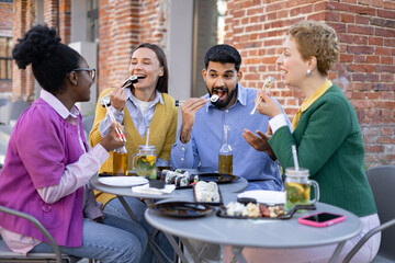 Friends enjoy sushi and drinks together at an outdoor restaurant.
