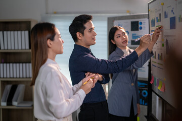 Fototapeta premium Three people are standing in front of a whiteboard with graphs and writing on it