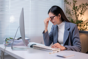 A woman is sitting at a desk with a computer monitor in front of her