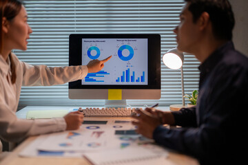 A woman points at a computer monitor with a graph on it