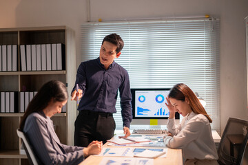 A man is talking to two women at a desk