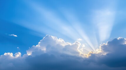Sunbeams piercing through clouds in a vibrant blue sky.