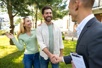 Happy couple greeting agent at new house in suburban setting