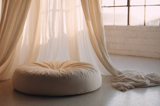 Round meditation cushion on clean floor with soft cotton drape, natural light streaming through large window, creating peaceful and serene atmosphere for relaxation or mindfulness practice