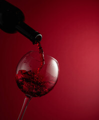 Pouring red wine from a bottle into a glass.