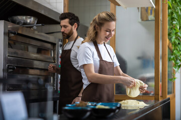 A man and woman prepare dough together in a modern bakery