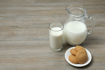 glass and jug with milk, cookies on wooden background