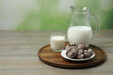glass and jug with milk, cookies on wooden background