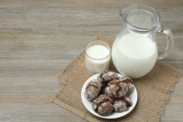 glass and jug with milk, cookies on wooden background